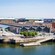 A waterfront with buildings, pedestrians and a bridge